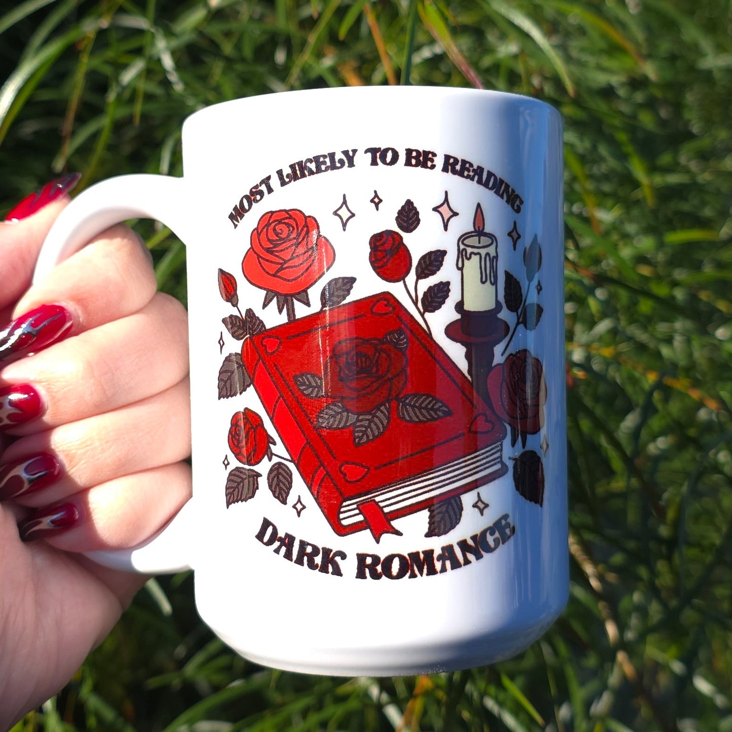 Hand holding a mug with a red and white design against a natural background